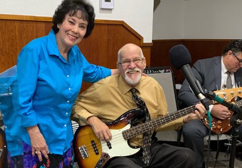 Pastor Joyce standing beside a smiling man playing bass guitar
