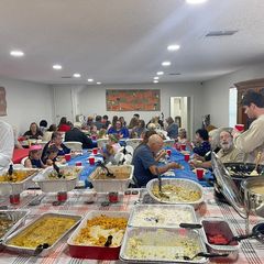 A fellowship meal, with tables of home-cooked dishes and the hall full of people eating