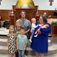 A family with their young children and a baby at the front of the church