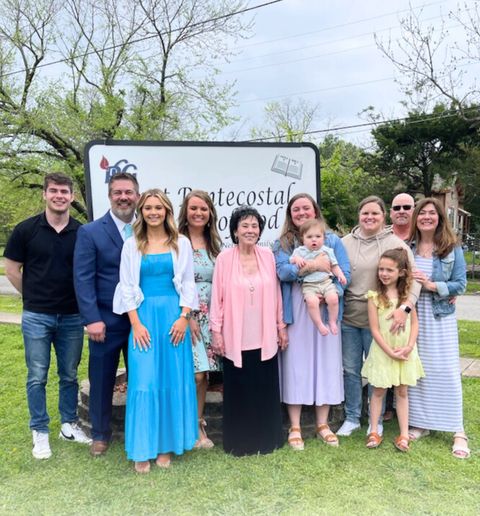 Pastor Joyce&rsquo;s family on the lawn in front of the church sign